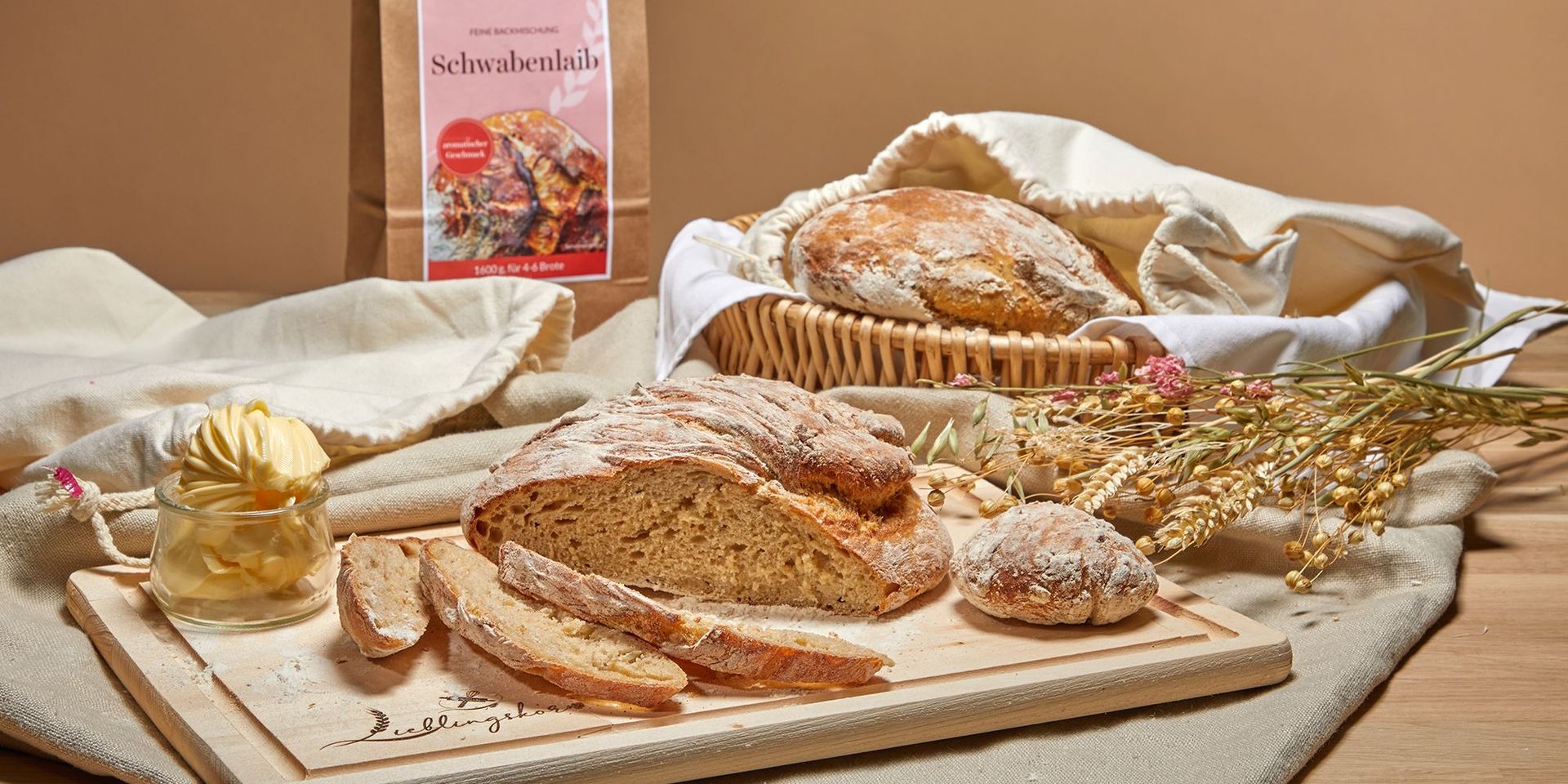 Leckeres Schwabenleib Brot, geschnitten auf einem Holzbrett. Dekoriert mit Butter und Getreide